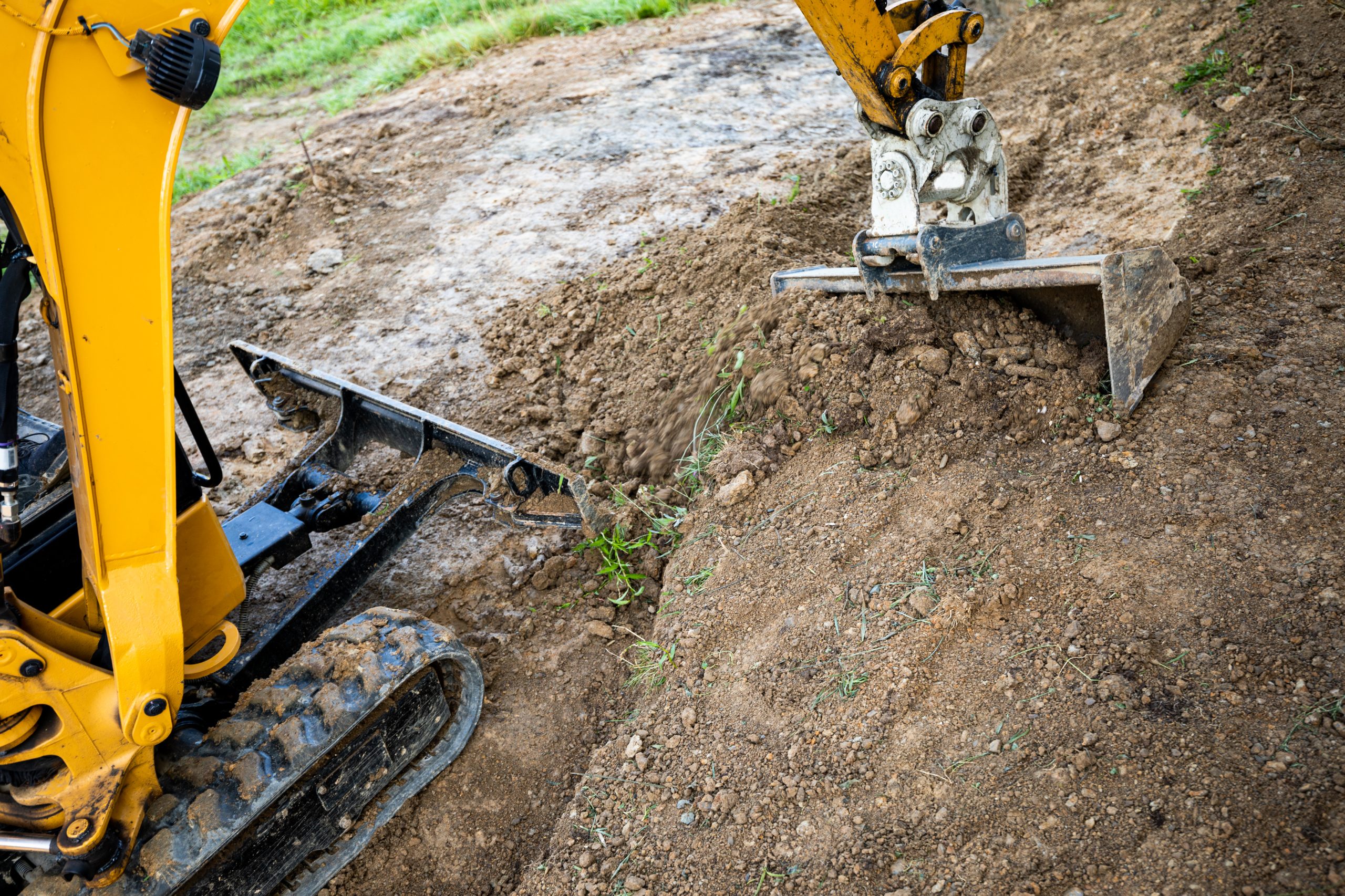 Mini excavator digging preparing ground under home garden
